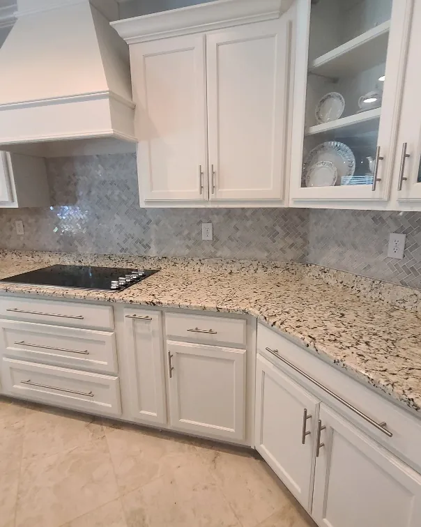 White kitchen remodel with a custom vent hood, glass-front cabinets, granite counters and a marble tile backsplash
