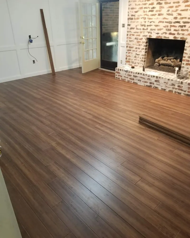 Open living room with new wood flooring and an exposed brick fireplace wall