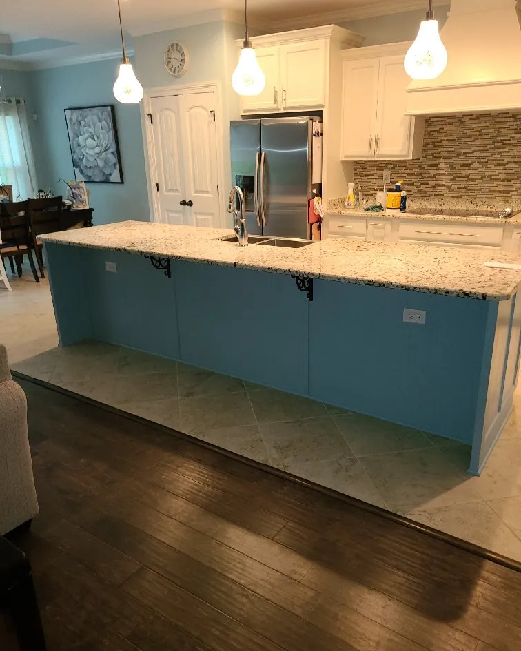 Open kitchen remodel with white cabinets, a teal painted island and granite counters