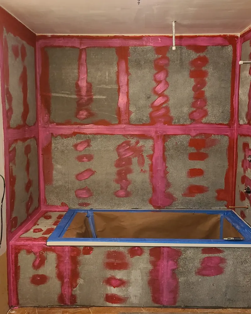 Red waterproofing membrane over a shower pan before any tile goes on