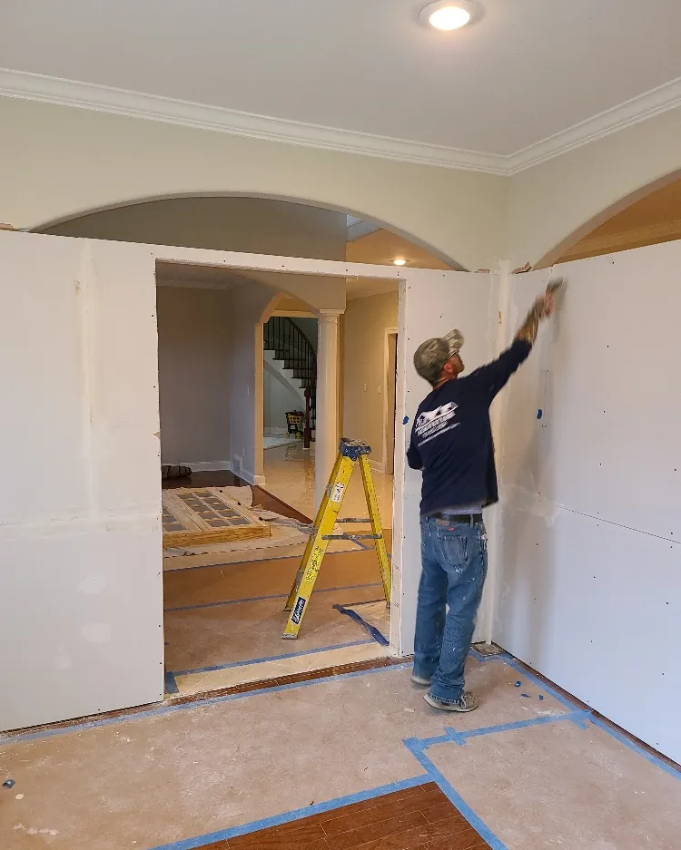 Painter cutting in a wall with drop cloths down and trim masked off