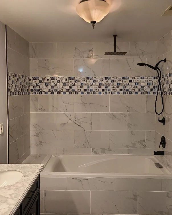 Garden tub with a marble tile surround and mosaic accent band in an Olive Branch, MS bathroom