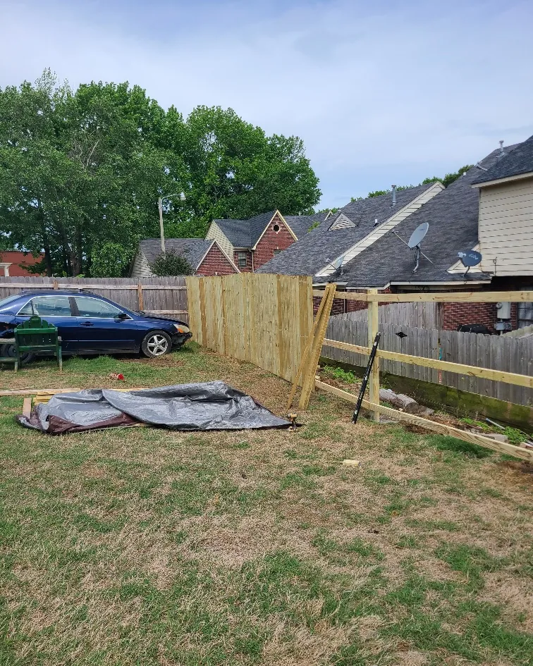 New wood privacy fence under construction with posts and rails set