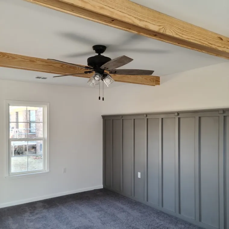 Board-and-batten accent wall with an exposed wood ceiling beam and new ceiling fan