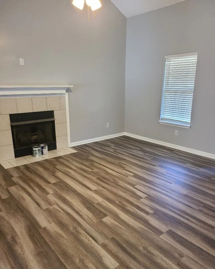 Renovated room with a tiled fireplace, fresh paint and new plank flooring