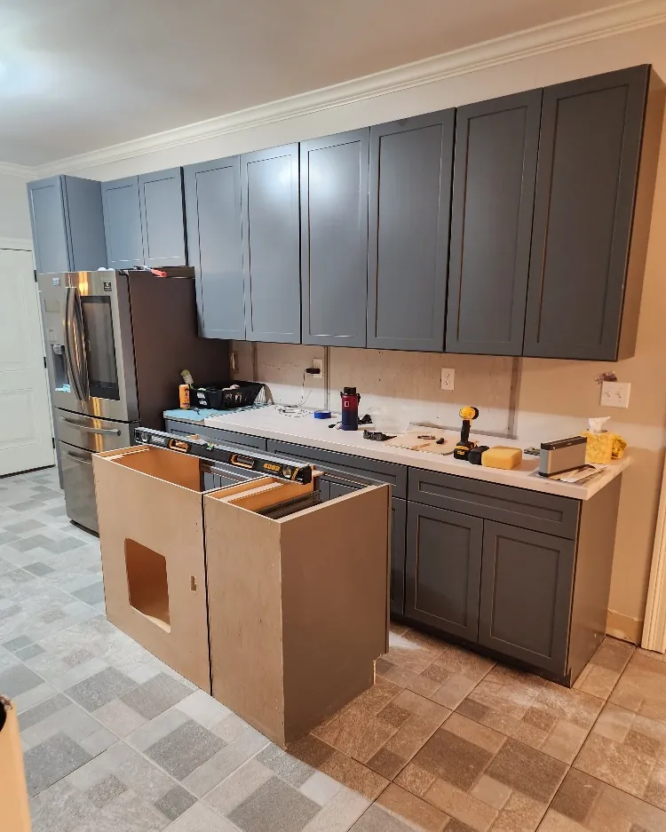 Kitchen cabinet installation in progress with new gray shaker cabinets and an island frame