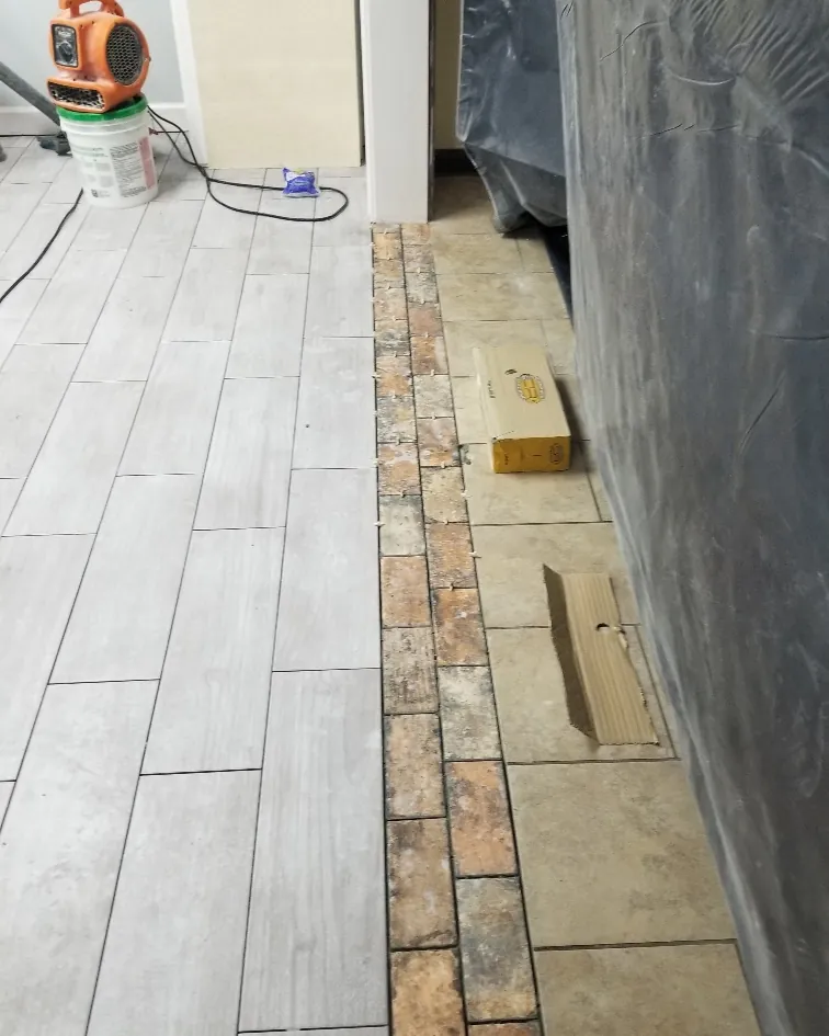 Frameless glass corner shower with marble subway tile and a pebble shower floor