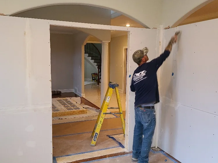Painter cutting in a wall with drop cloths down and trim masked off